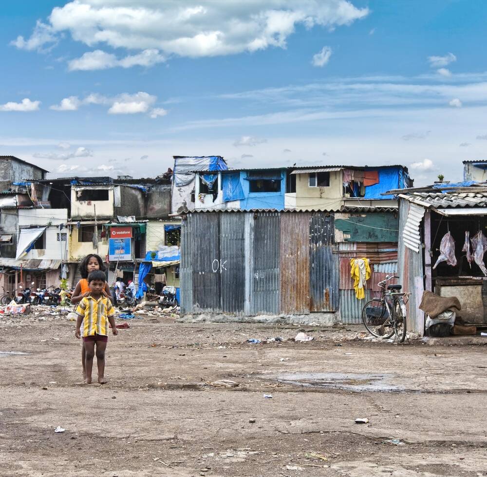 Two children standing in front of slum houses.
